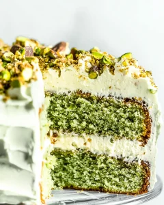A whole cake with pistachio butter topped with buttercream and chopped pistachios.