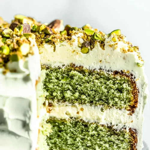 Ultimate Cake with Pistachio Butter Recipe 5 A whole cake with pistachio butter topped with buttercream and chopped pistachios.
