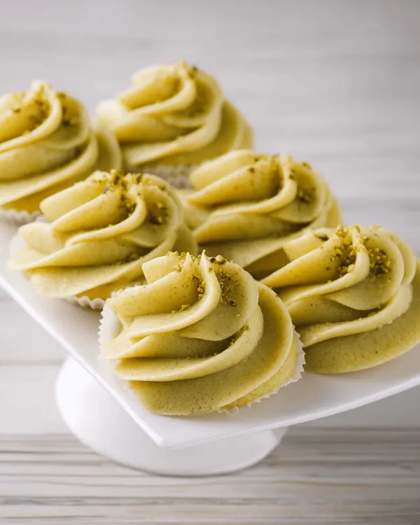 Ultimate Pistachio Cream Butter Recipe 4 Vanilla cupcakes topped with pistachio cream butter frosting in elegant rosette swirls, garnished with chopped pistachios