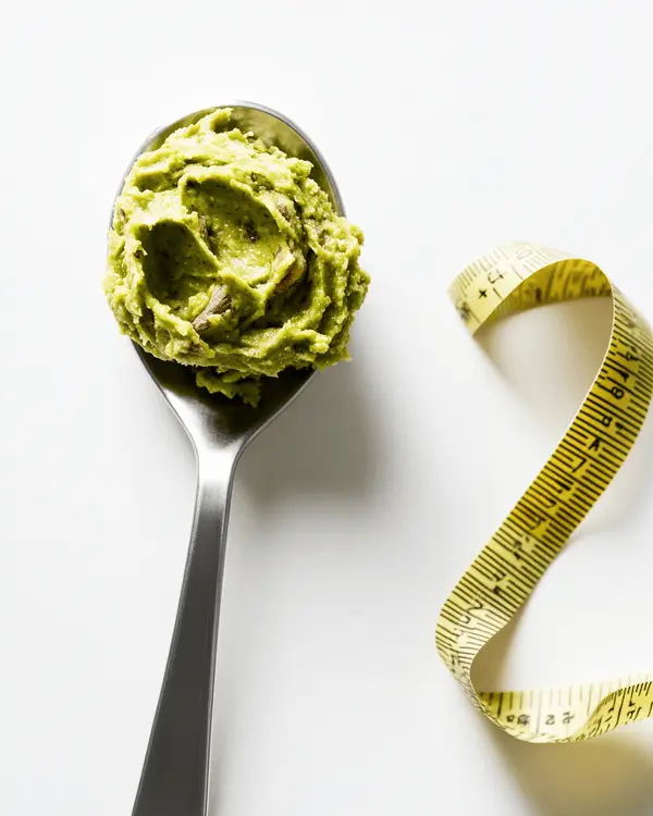 Pistachio Butter Benefits: 7 Health Rewards 4 Measured portion of pistachio butter on spoon with measuring tape showing portion control for weight management