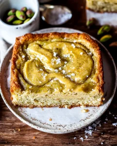 Baked pistachio cream gooey butter cake in pan with golden edges and swirled pistachio top.