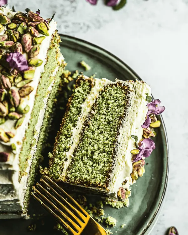 Ultimate Cake with Pistachio Butter Recipe 4 Slices of pistachio butter cake served with pistachio garnish and flowers.