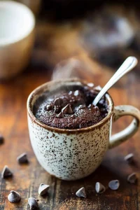 Hero shot of rich chocolate mug cake with almond meal with melted chocolate chips and fudgy texture in dramatic lighting