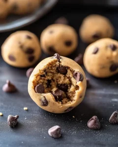 Close-up of no bake chocolate chip cookie dough ball with bite taken showing soft, safe-to-eat texture and chocolate chips throughout