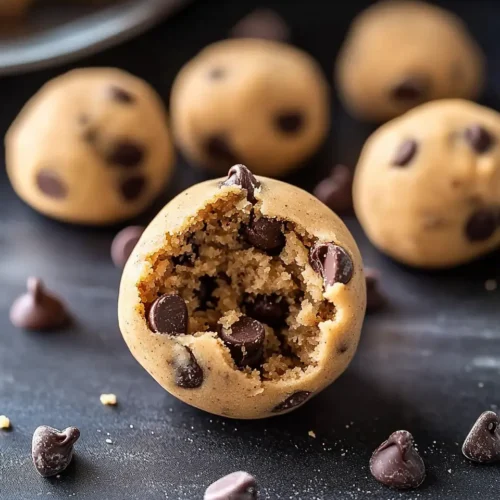 Close-up of no bake chocolate chip cookie dough ball with bite taken showing soft, safe-to-eat texture and chocolate chips throughout