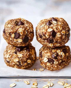 Stack of four no bake lactation cookies showing texture with visible oats and chocolate chips on parchment paper