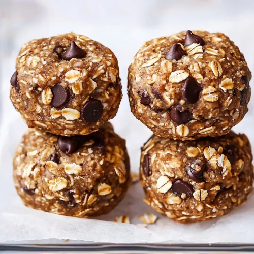 Stack of four no bake lactation cookies showing texture with visible oats and chocolate chips on parchment paper