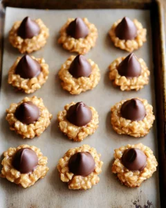Overhead view of freshly made no bake peanut butter kiss cookies on parchment-lined baking sheet with chocolate kisses centered on each cookie