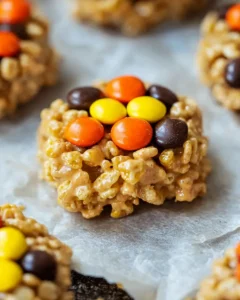Close-up hero shot of a single no bake rice crispy cookie showing detailed texture of cereal pieces and colorful Reese's Pieces bound with golden peanut butter mixture