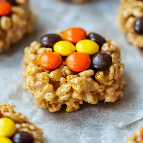 Close-up hero shot of a single no bake rice crispy cookie showing detailed texture of cereal pieces and colorful Reese's Pieces bound with golden peanut butter mixture