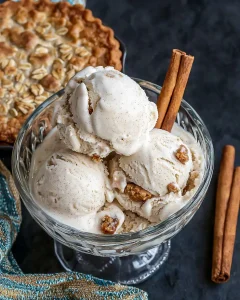 Three scoops of homemade oatmeal cream pie ice cream in glass bowl showing creamy texture and cookie pieces throughout