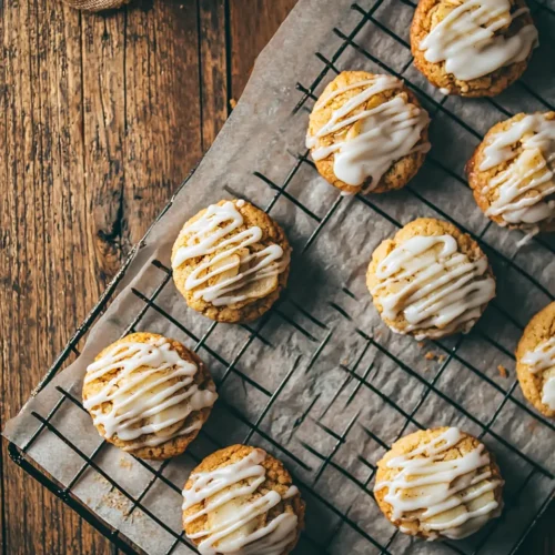Freshly baked cinnamon apple cookies with maple icing cooling on wire rack in rustic kitchen setting
